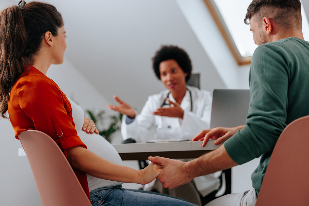 Couple en consultation avec un professionnel de santé pendant la grossesse